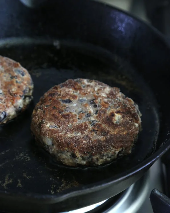 2 black bean burgers on a black pan