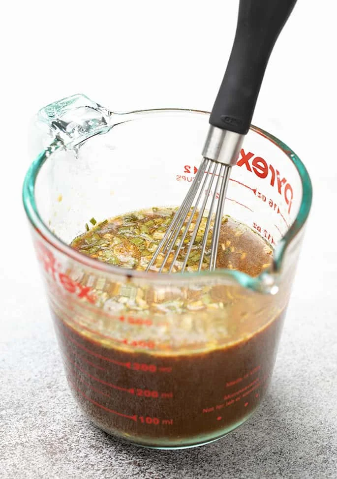 2 cup glass measuring cup with brown sauce and whisk