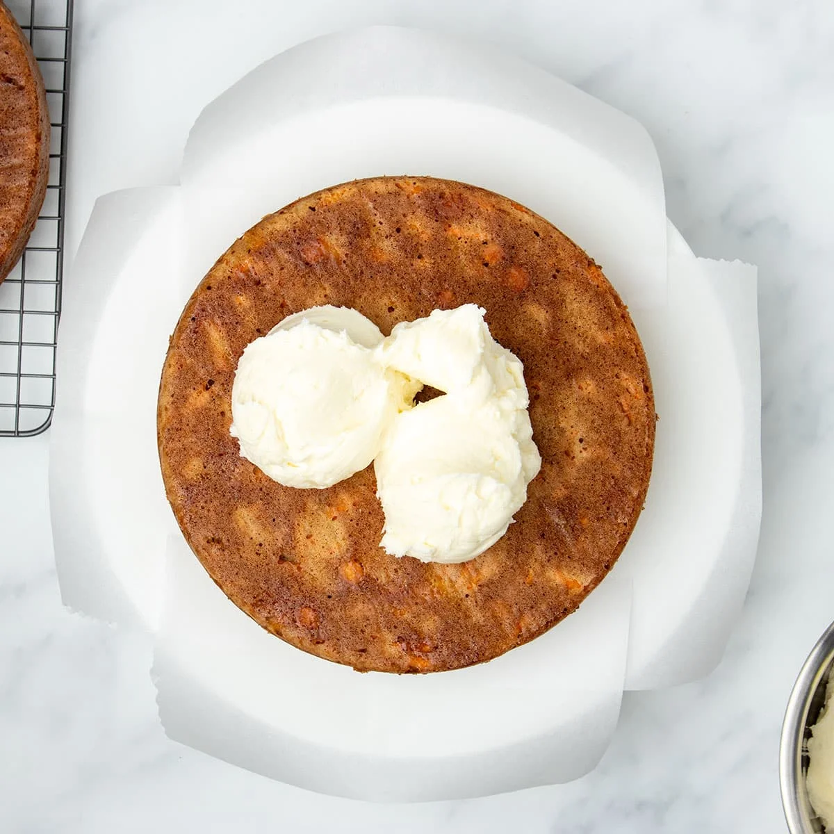 3 scoops of white cream cheese icing in center of overturned baked brown cake.