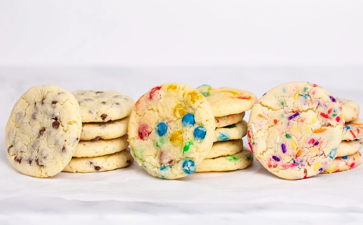 3 tacks of 4 cookies with one cookie on its side leaning against rest of stack, all with different mix-ins.