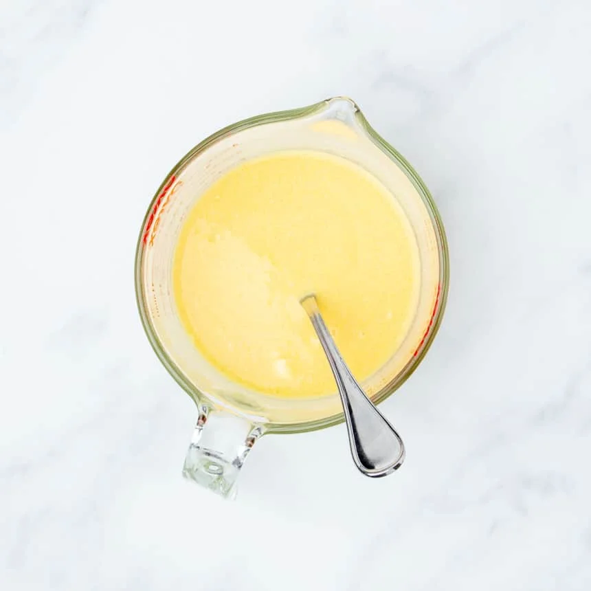 4 cup glass measuring cup with handle with yellow liquid with handle of metal fork sticking out