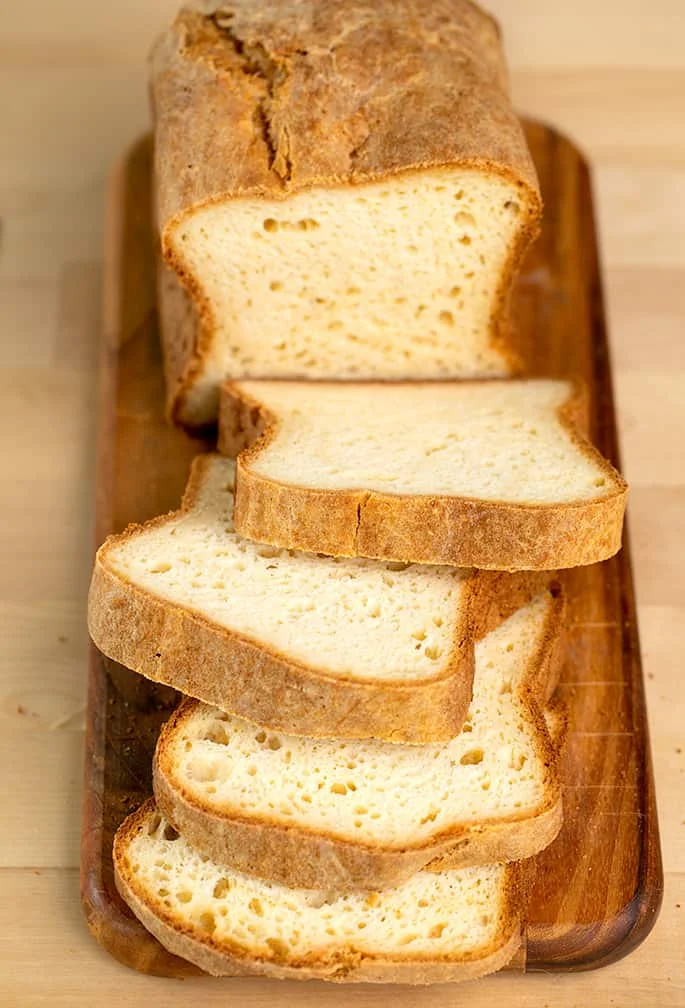 4 slices of potato bread with rest of whole loaf on brown cutting board,