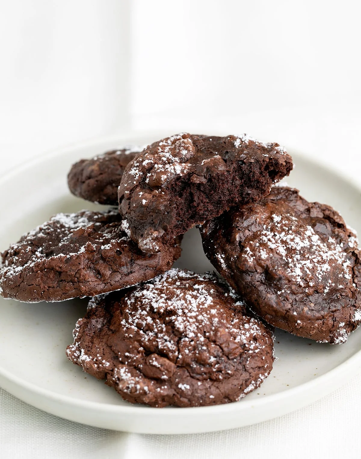 5 chocolate cookies on a small white plate one with a bite taken