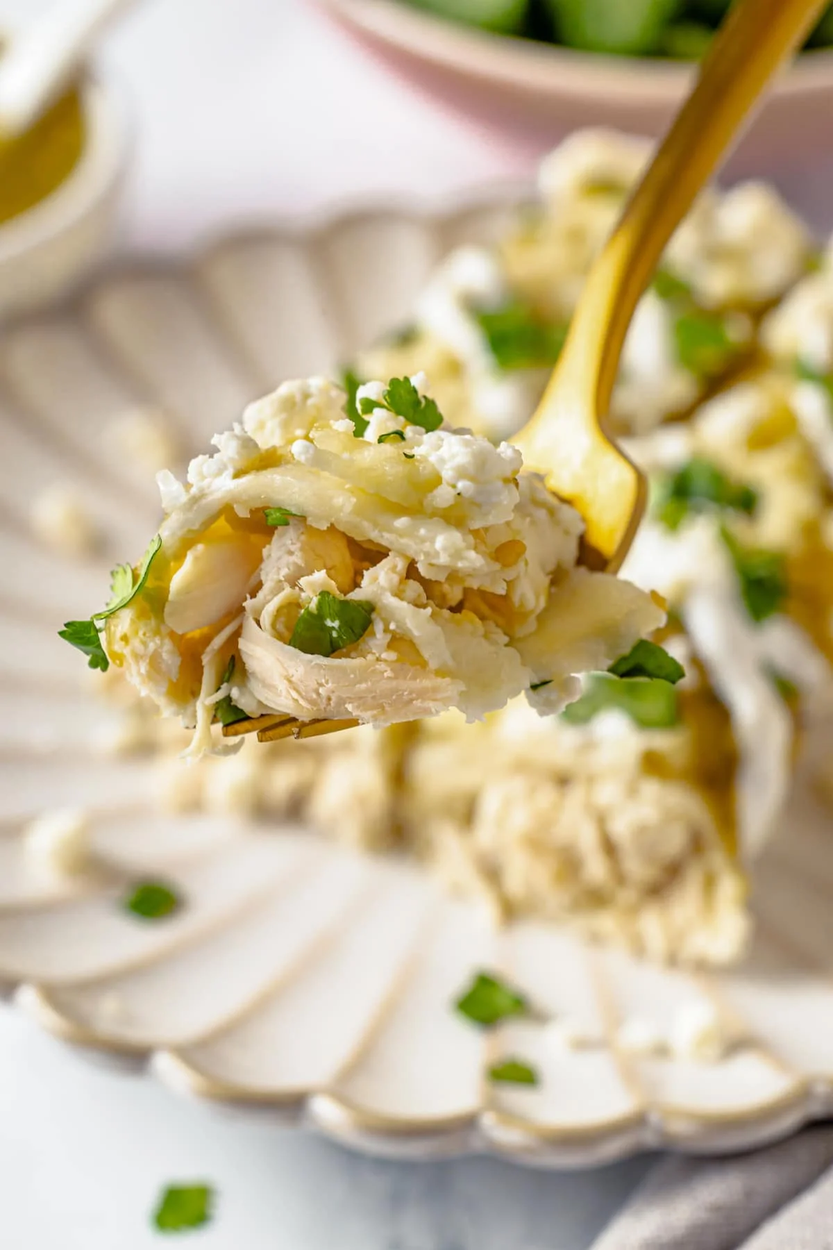 A bite of a green chicken enchilada on a fork