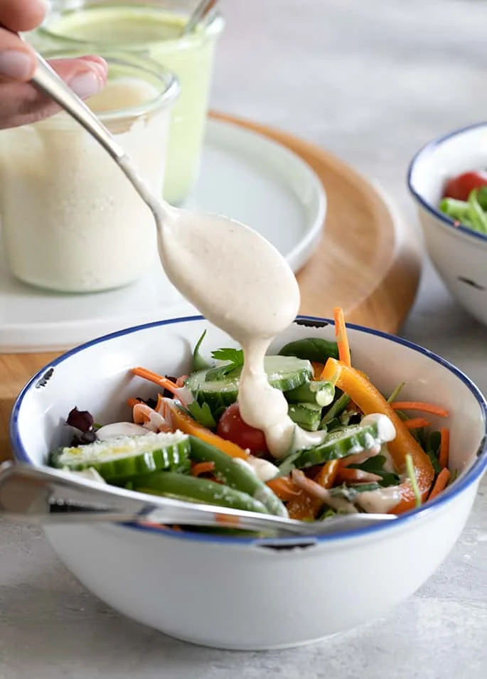 A bowl of food on a table, with Salad and Salad dressing