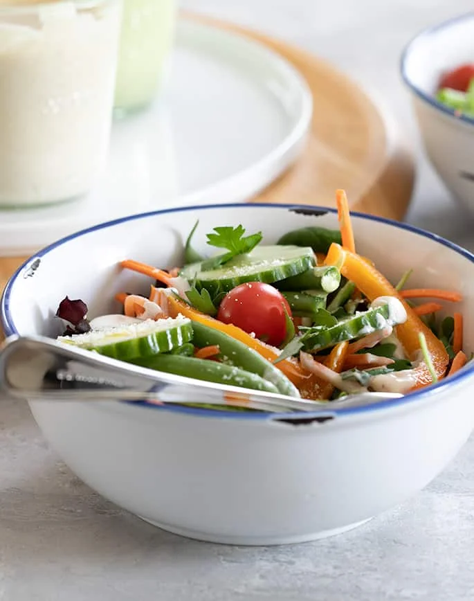 A bowl of salad in a plate with a fork