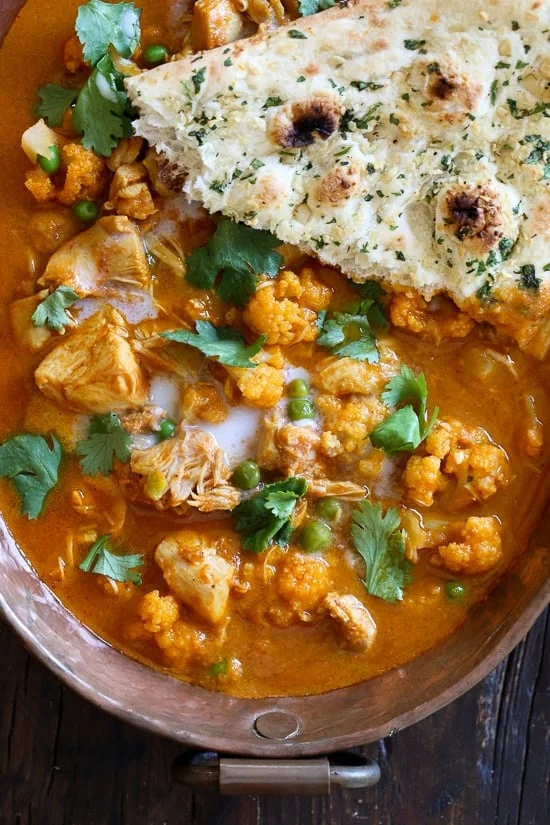A bowl of tikka masala with a slice of naan