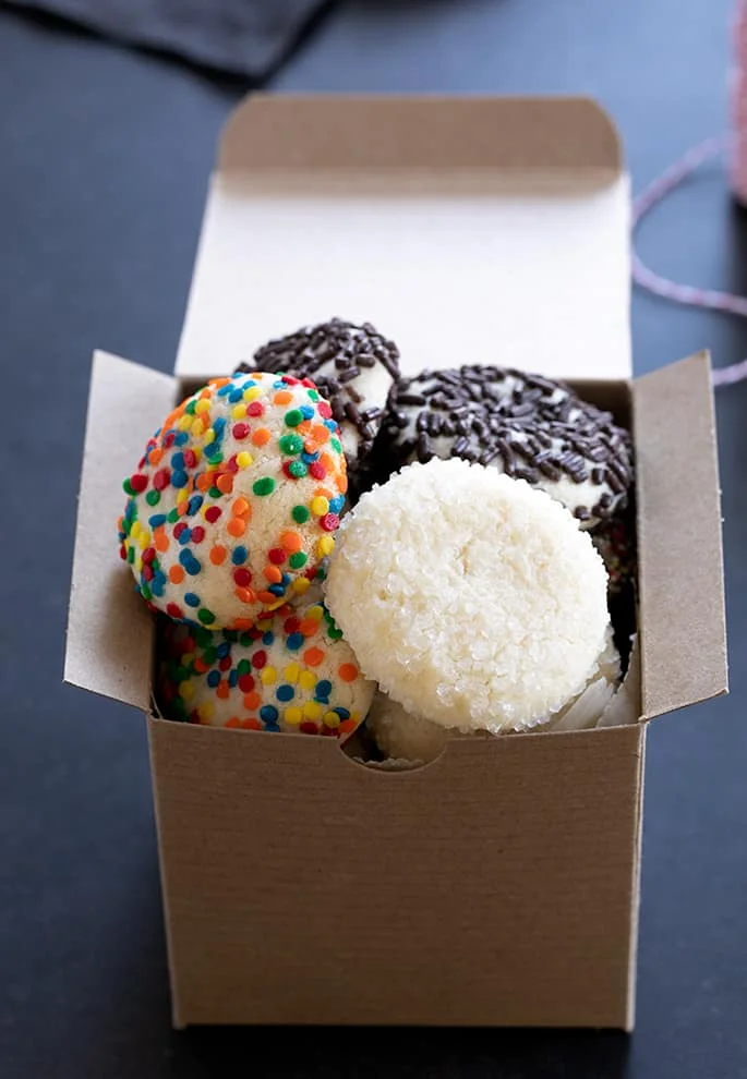 A box of drop sugar cookies with different toppings.