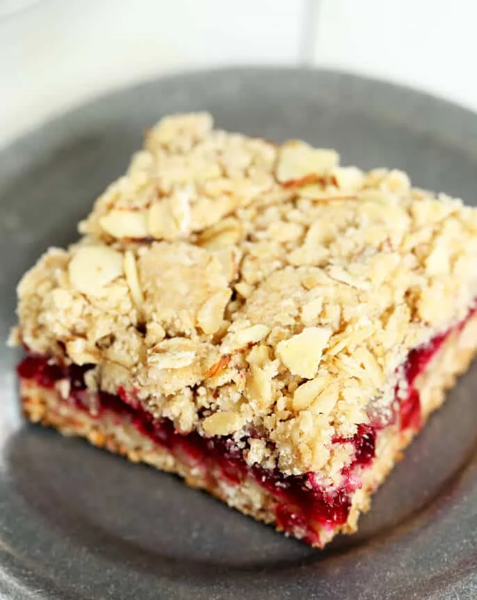 A close up of a cranberry jam bar on a dark silver plate 