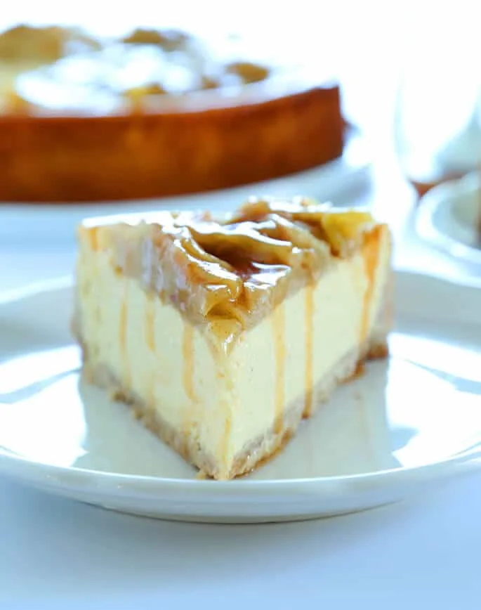 A close up of a slice of apple cinnamon cheesecake on a white plate