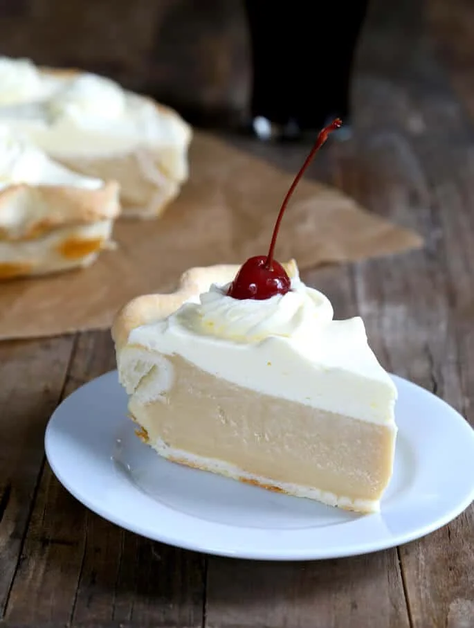 A close up of a slice of root beer pie with cherry on top on white plate.