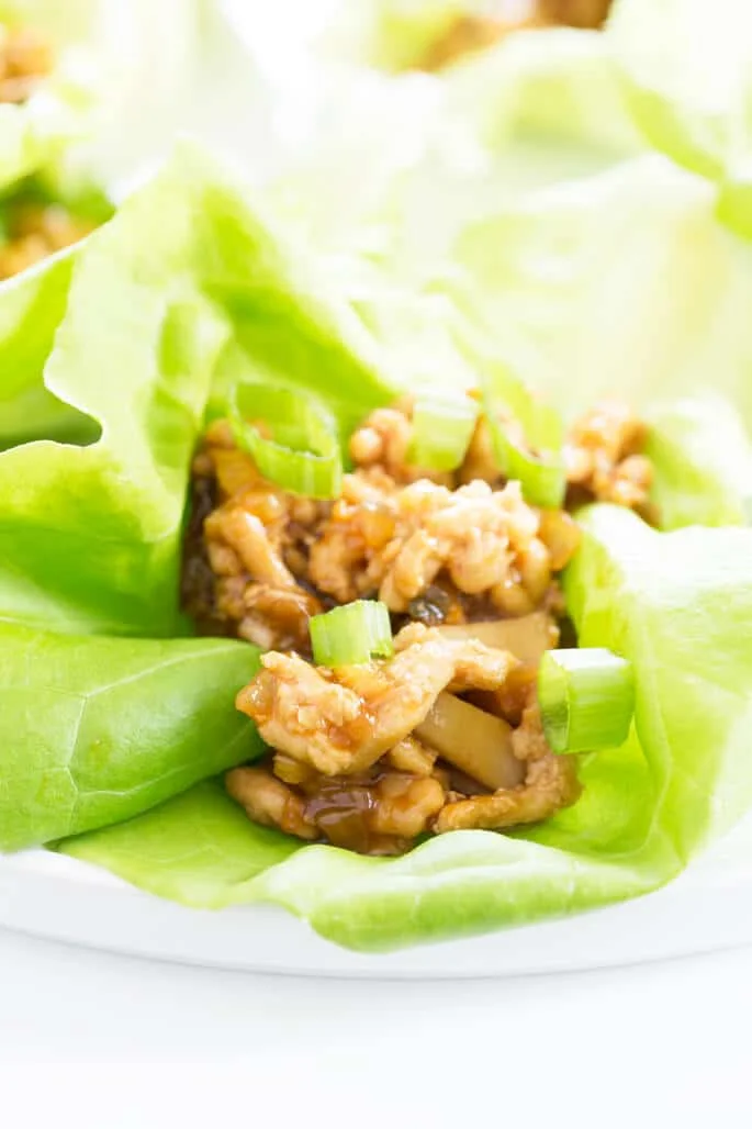 A close up of asian chicken lettuce wraps on a white plate 