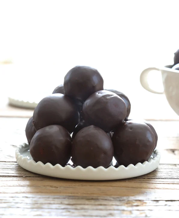 A close up of chocolate donut holes in white plate 