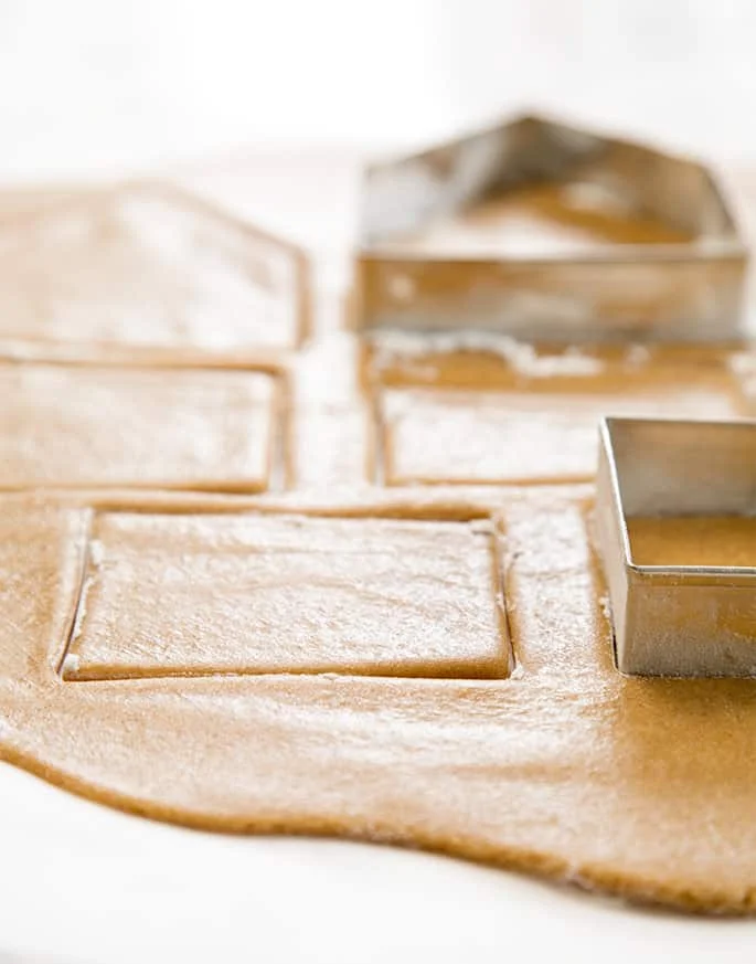 A close up of gingerbread cookie dough with cookie cutters
