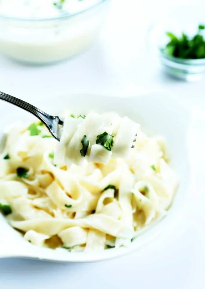 A close up of noodles with the sauce on a metal fork .