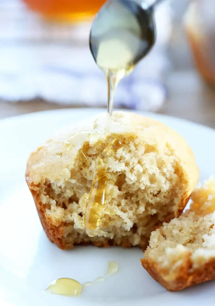 A close up of the inside of a honey muffin on a white plate with honey on it