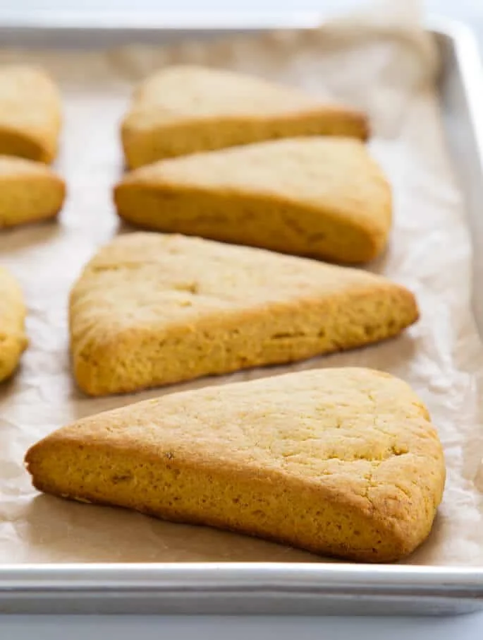 A close up side view of pumpkin scones on parchment paper 