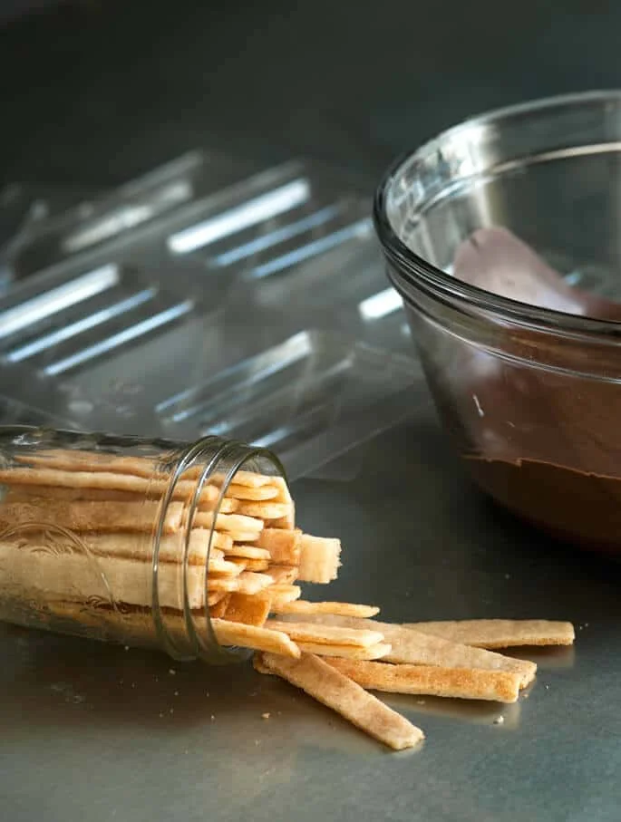 A jar with vanilla wafers and a bowl of melted chocolate 