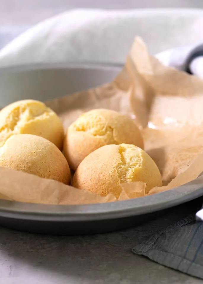 A round tin with brown paper and 4 pan de bono rolls