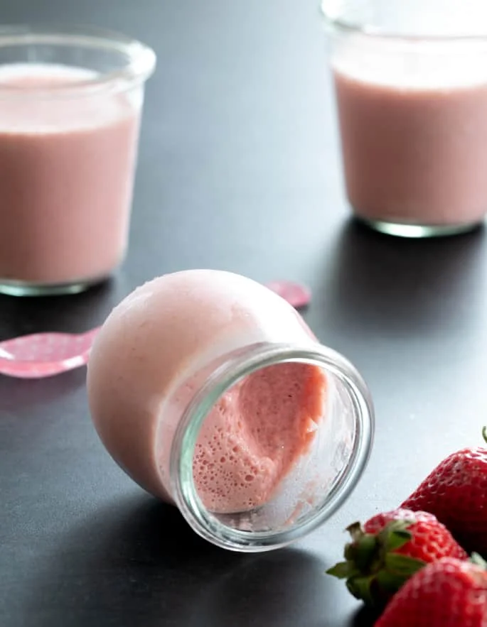 A small jar of whipped strawberry jello on its side.