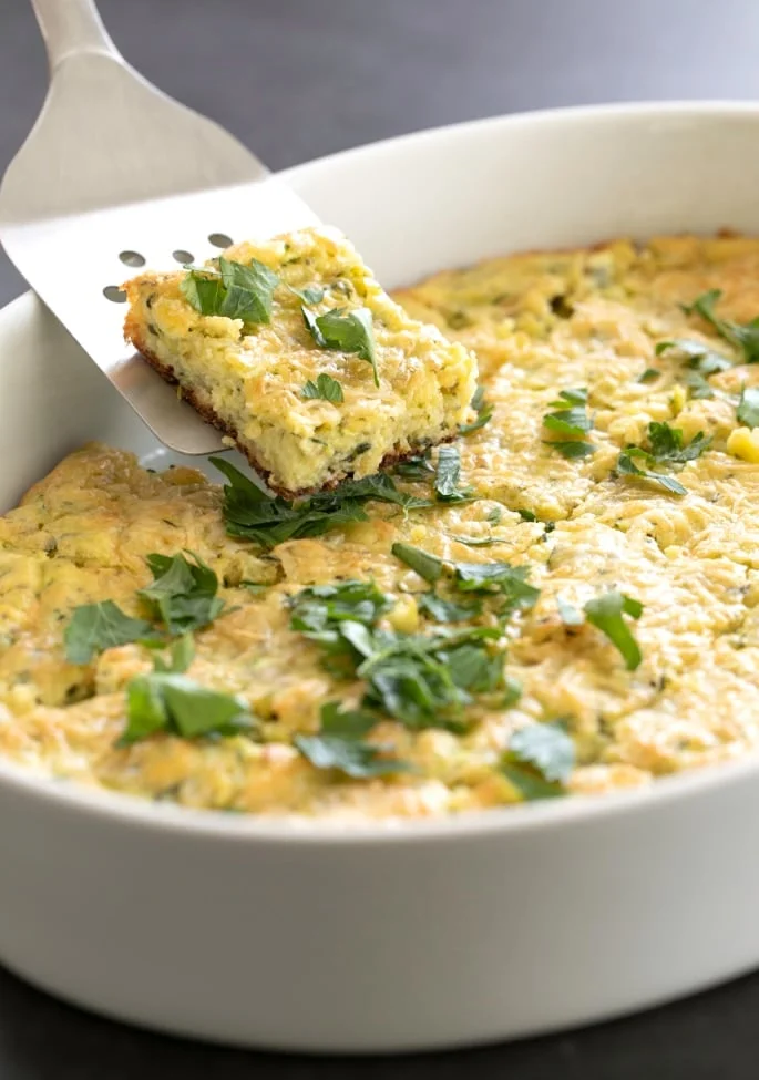 A spatula taking a square of zucchini parmesan bake from a dish