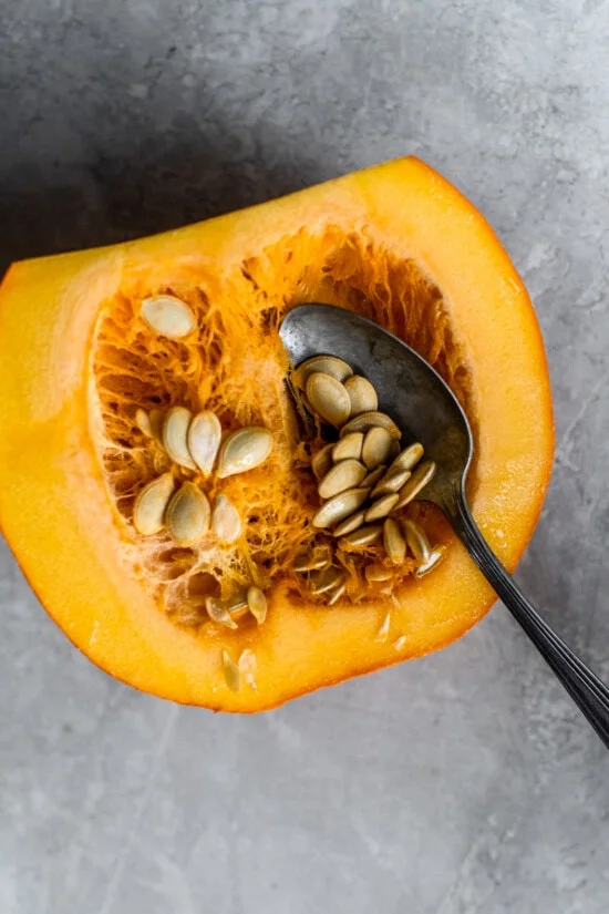 A spoon scooping out the seeds from a pumpkin
