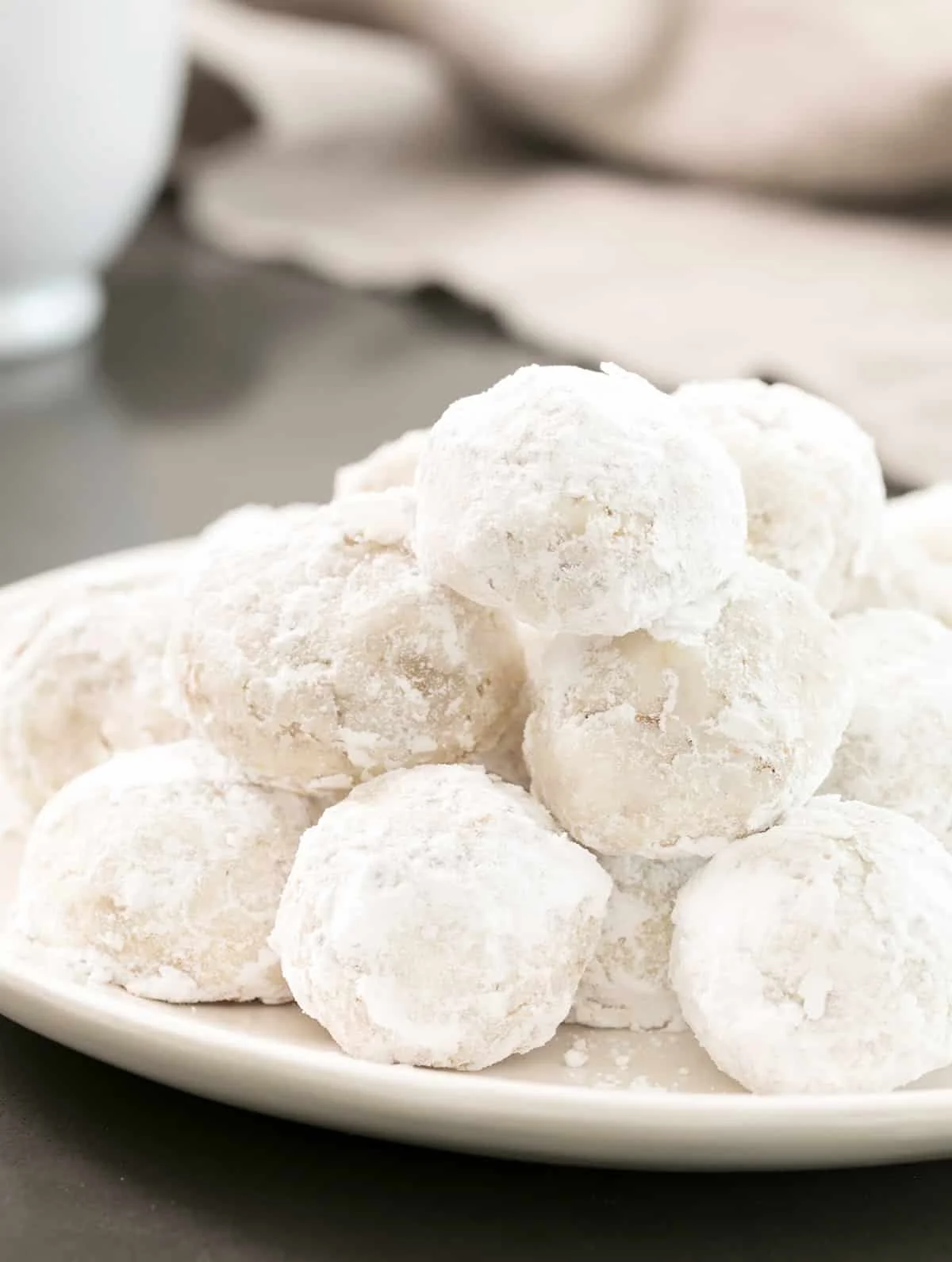 A white plate full of gluten free Mexican wedding cookies.
