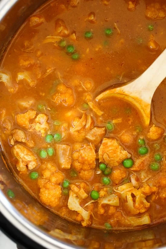 A wooden spoon stirring chicken tikka masala in the Instant Pot