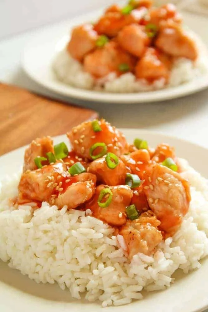 Air Fried Sweet and Sour Chicken with rice underneath on a white plate