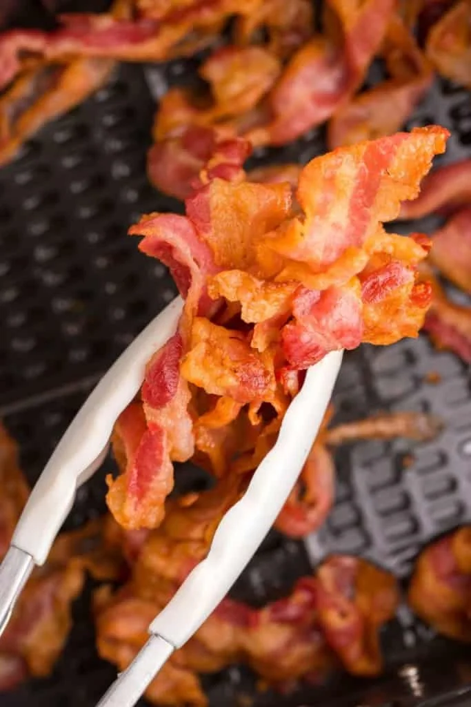 air fryer bacon being held by tongs