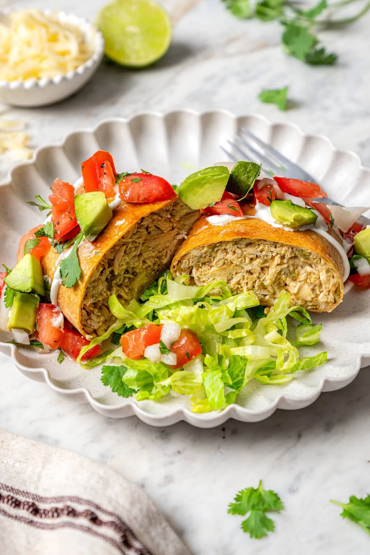 Air fryer chicken chimichanga cut in half on plate with lettuce and toppings