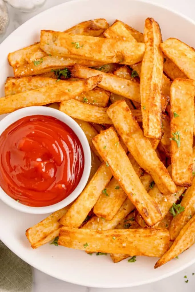 Air fryer fries on a white plate with ketchup.