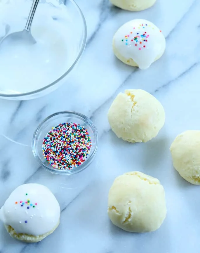 Anisette cookies on marble surface with bowl of nonpareils 