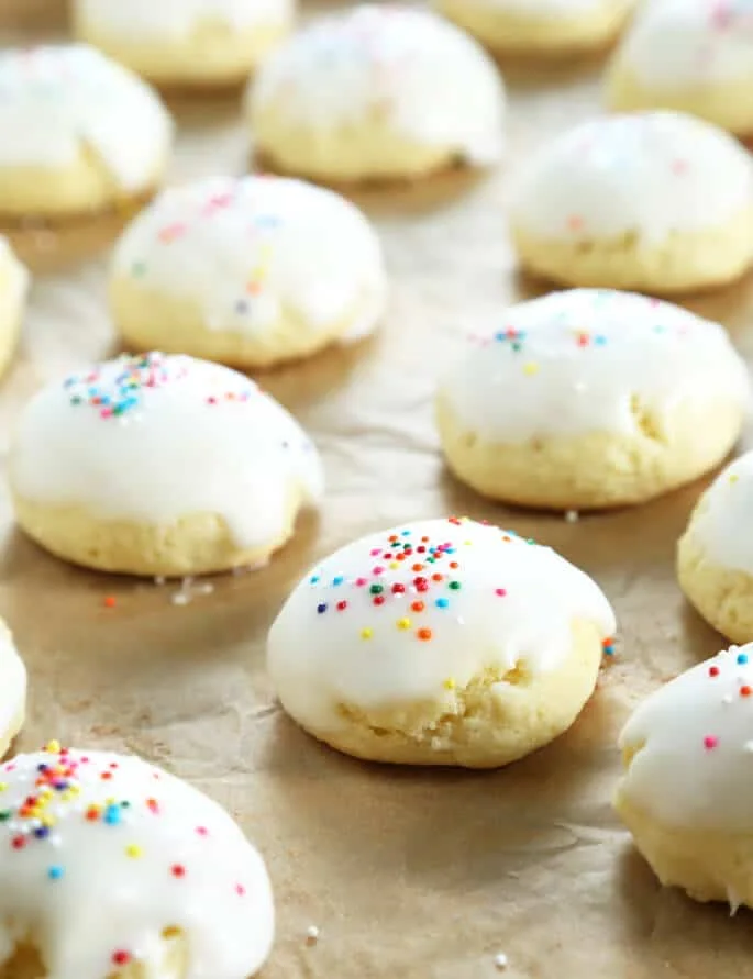 Anisette cookies wit frosting and nonpareils on parchment paper 
