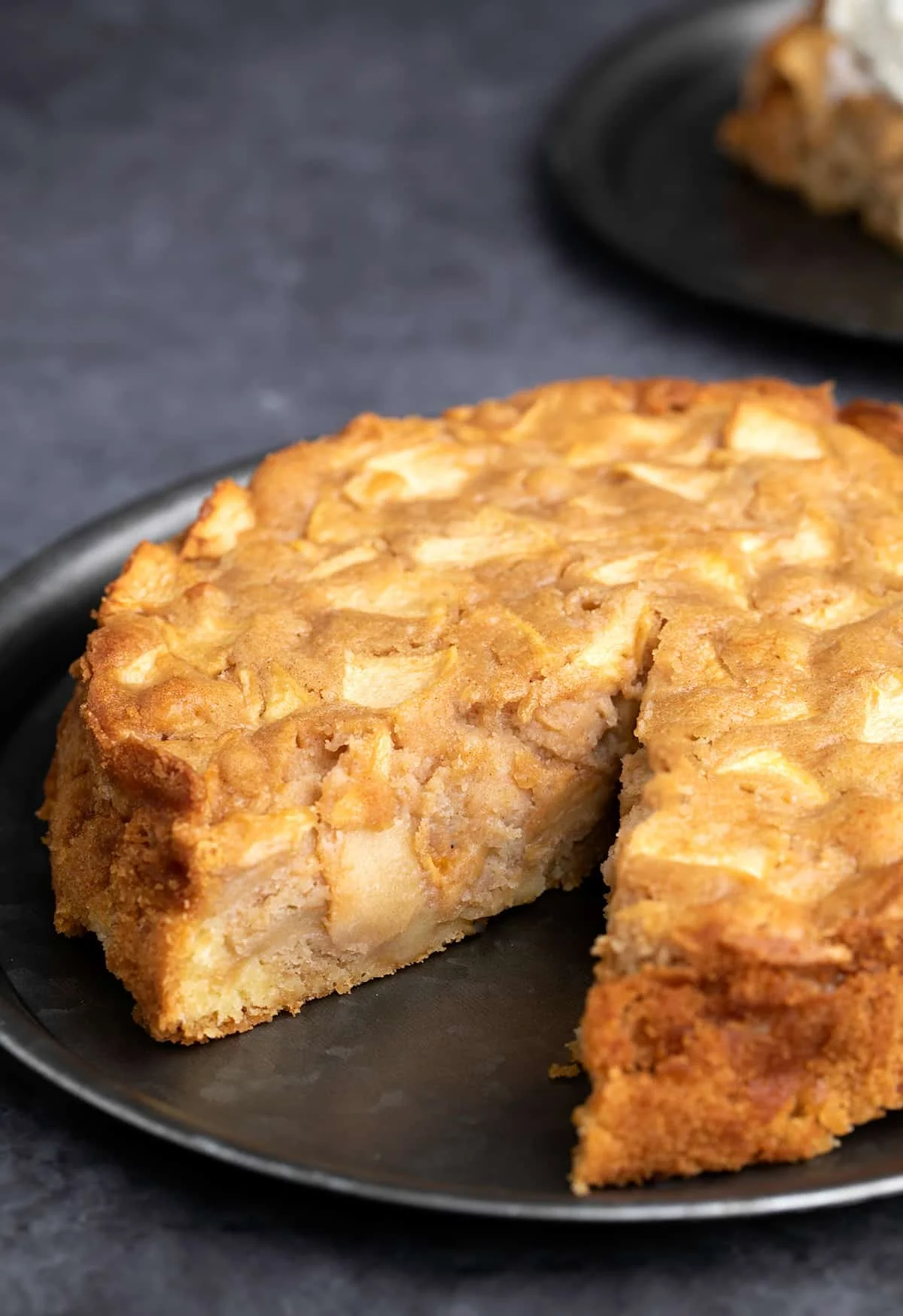 Apple cake with slice missing on black serving plate