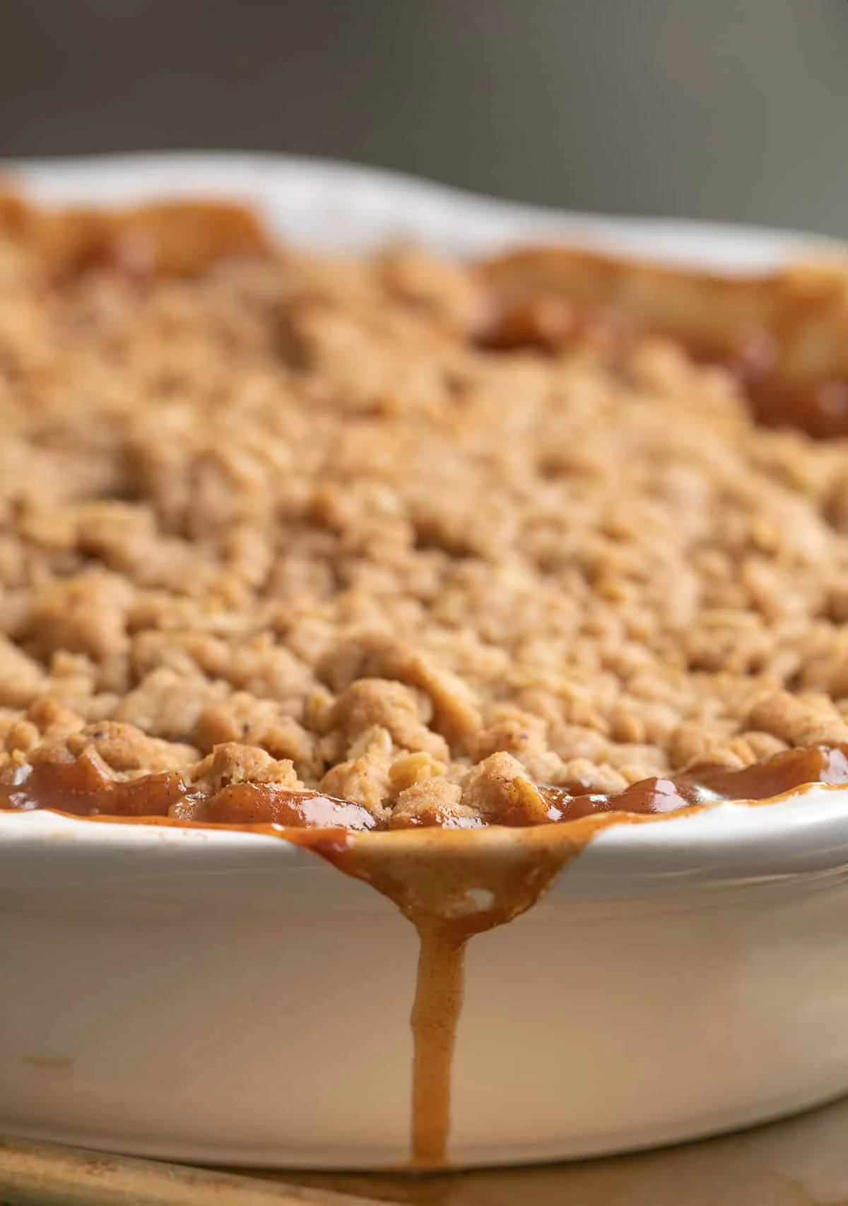 Apple crisp in baking dish on metal tray with caramelized filling.