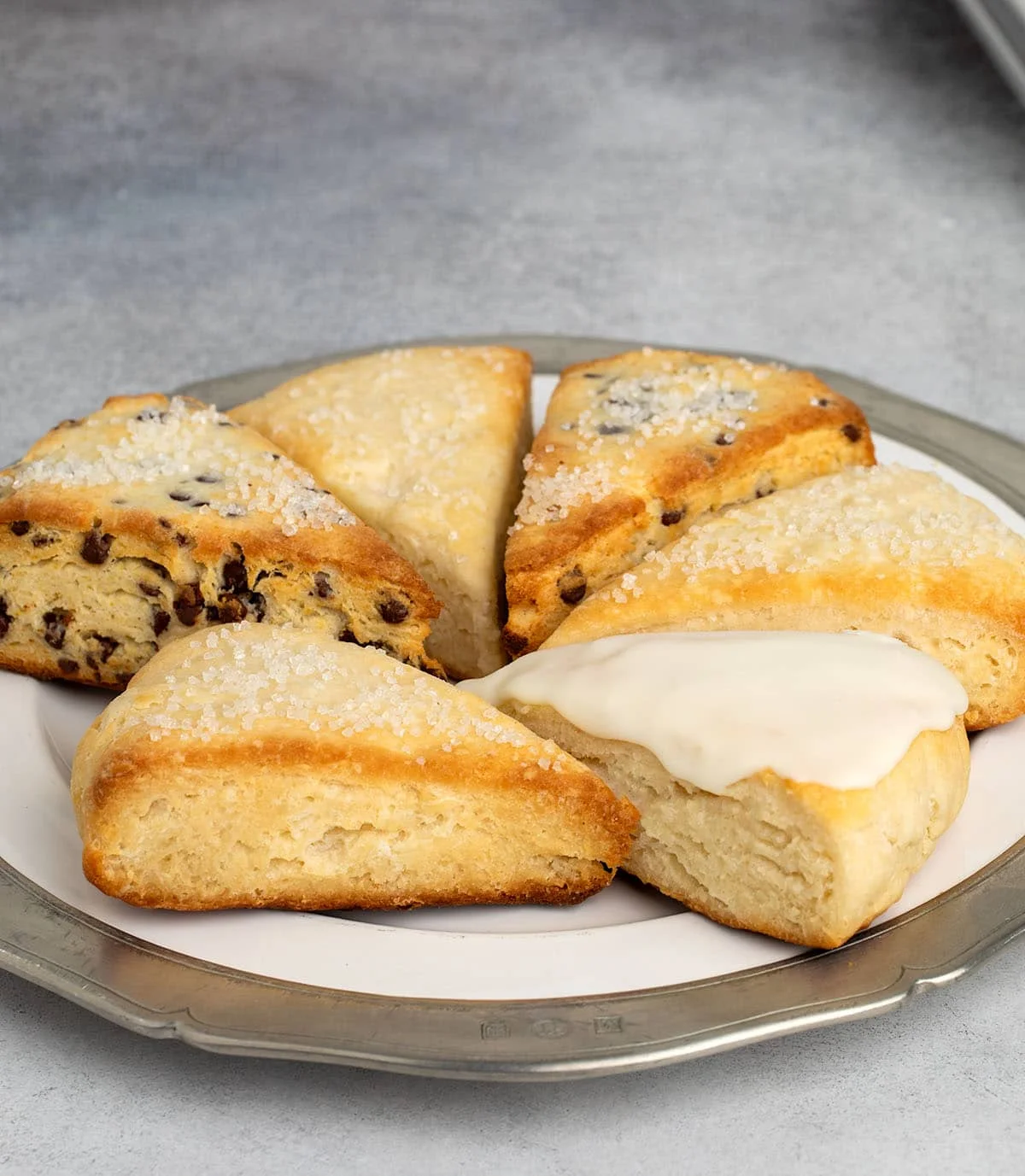 Assorted scones on a plate, including plain, chocolate chip, and one with vanilla glaze.