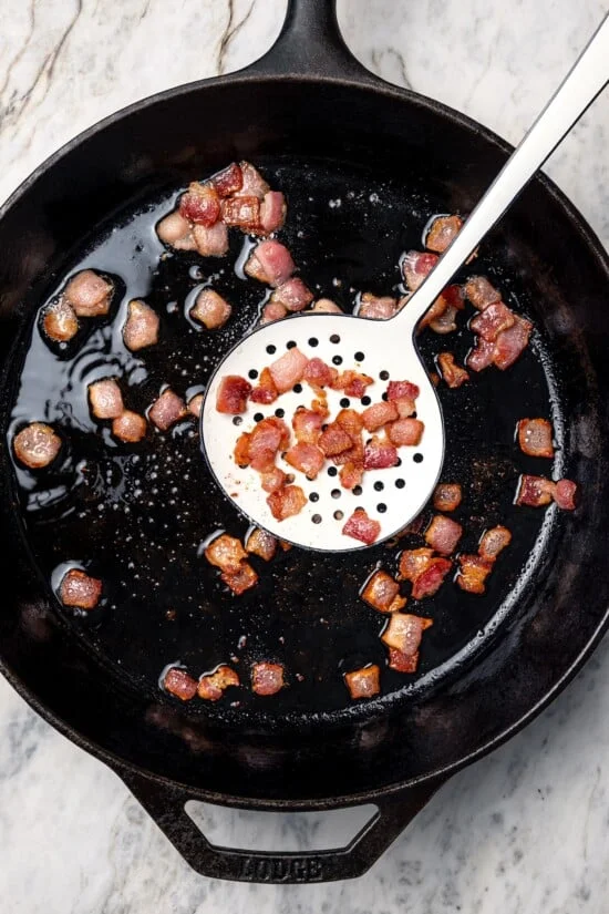 Bacon being removed from skillet.