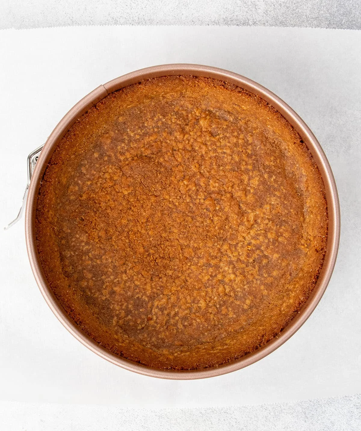 Baked brown graham cracker crust in round gold springform pan.