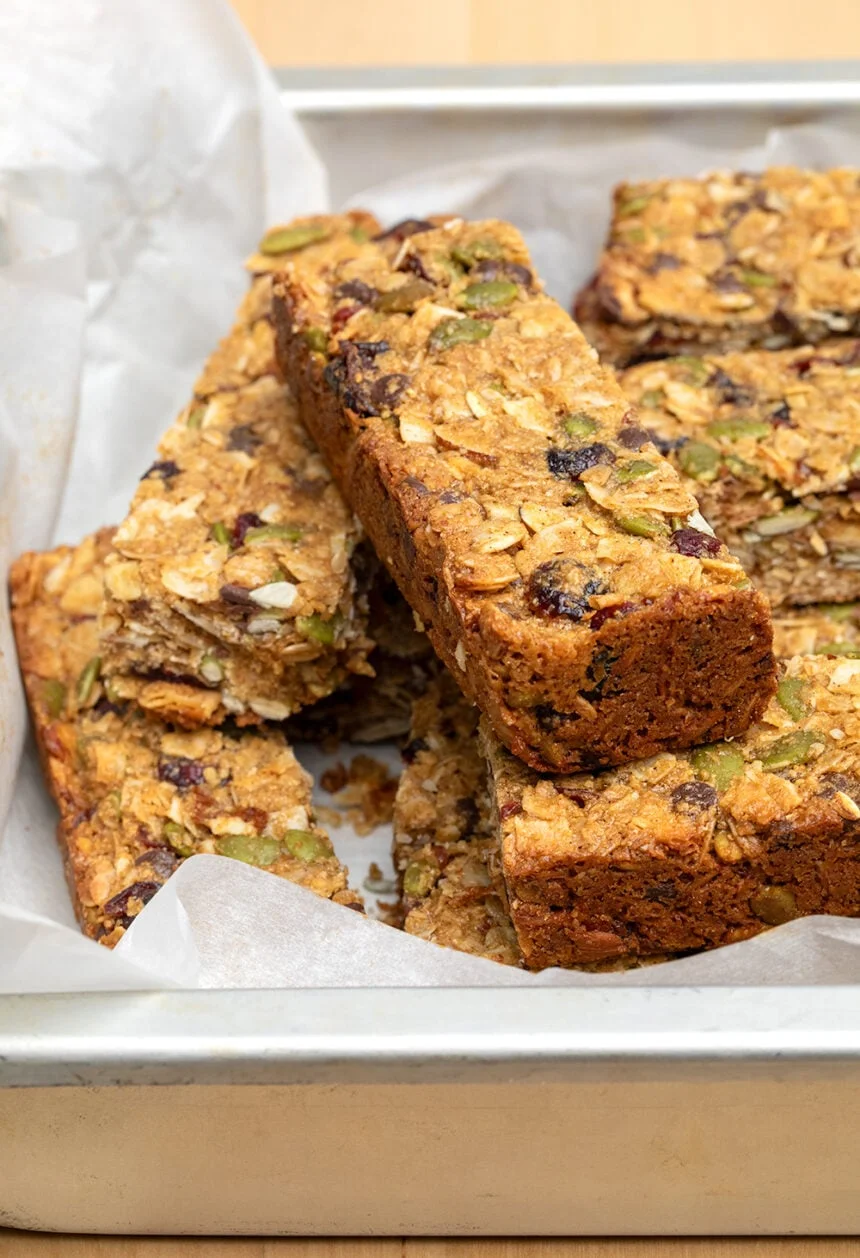 Baked brown granola bars with nuts and berries in white paper in metal baking tray