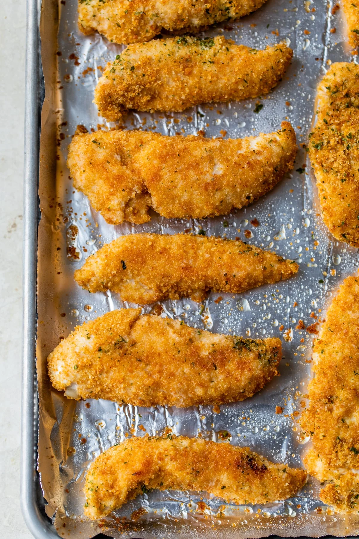 Baked chicken tenderloins on a baking sheet