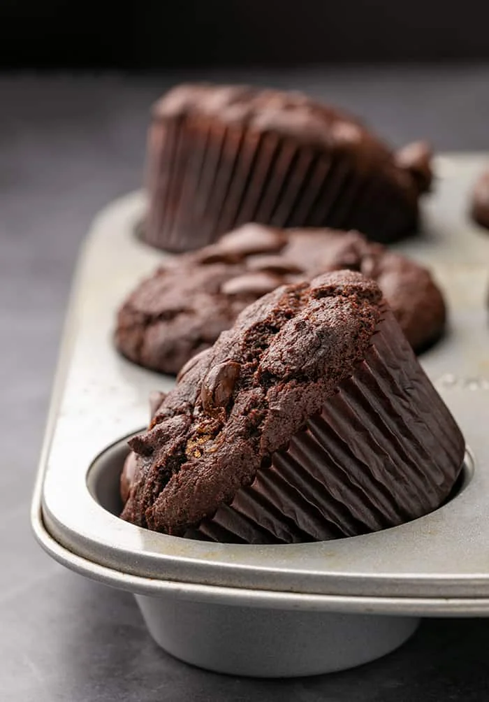 Baked gluten free chocolate muffins in metal tin with some on their sides