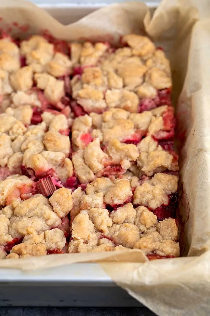 Baked strawberry rhubarb crisp in metal pan cut into squares