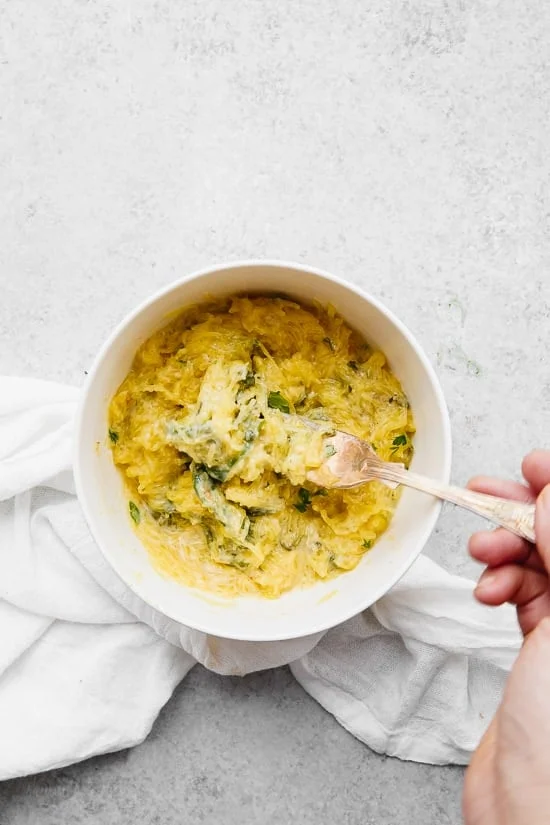 Bowl of cheesy baked spaghetti squash with green vegetables