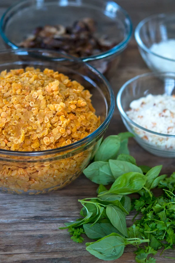 Bowl of lentils and greens on side on wooden surface 