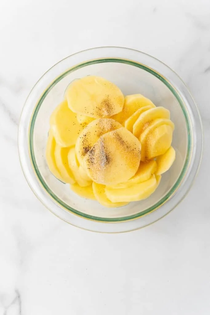 bowl with sliced potatoes and seasonings
