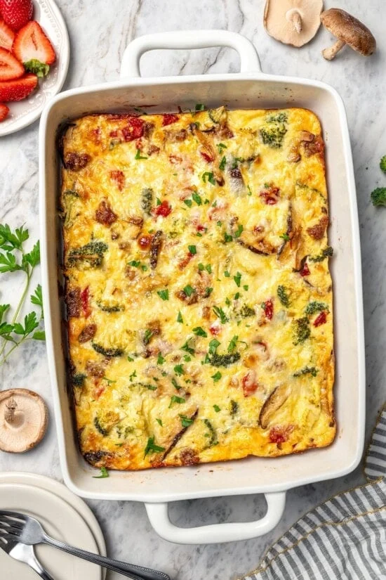 Breakfast casserole with sausage, cheese, and veggies in baking dish.