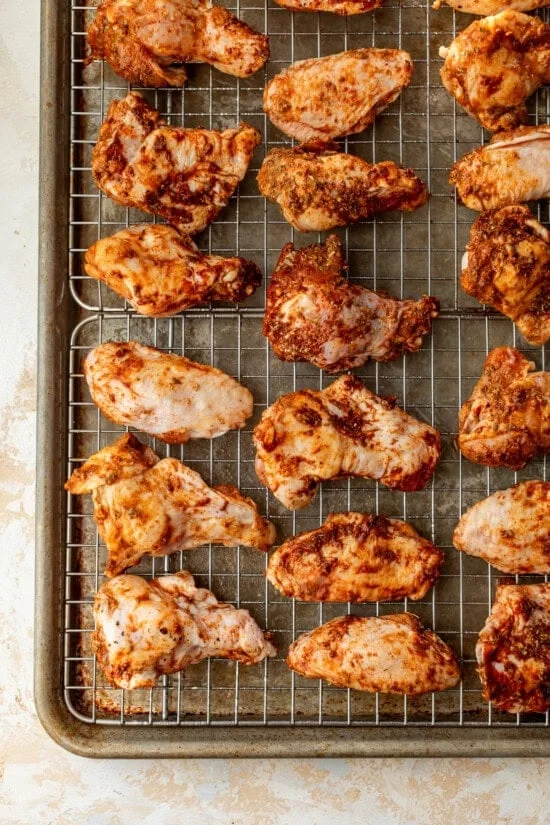 Broiled chicken wings on wire racks set on top of baking sheets.