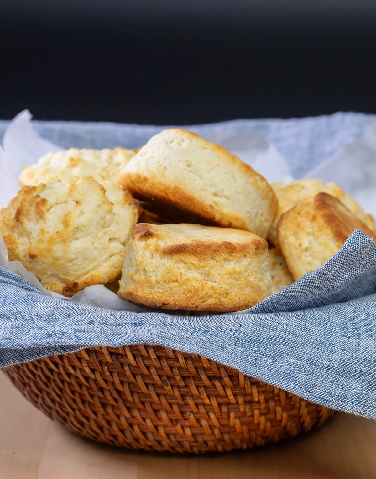Brown bowl with blue cloth liner filled with round and drop biscuits.