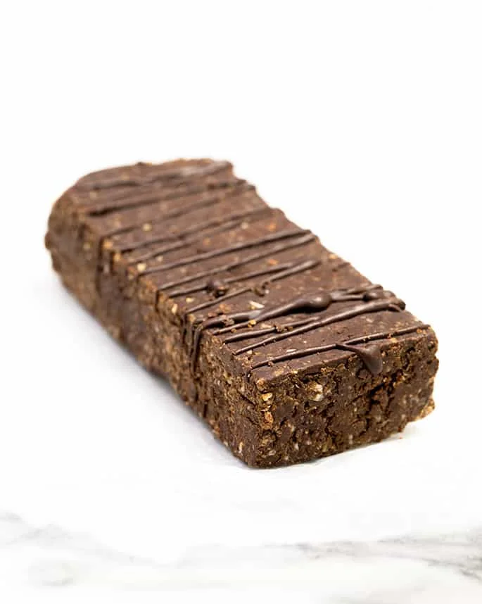 Brown homemade protein bars made with chocolate drizzle made with protein bar recipe on white surface